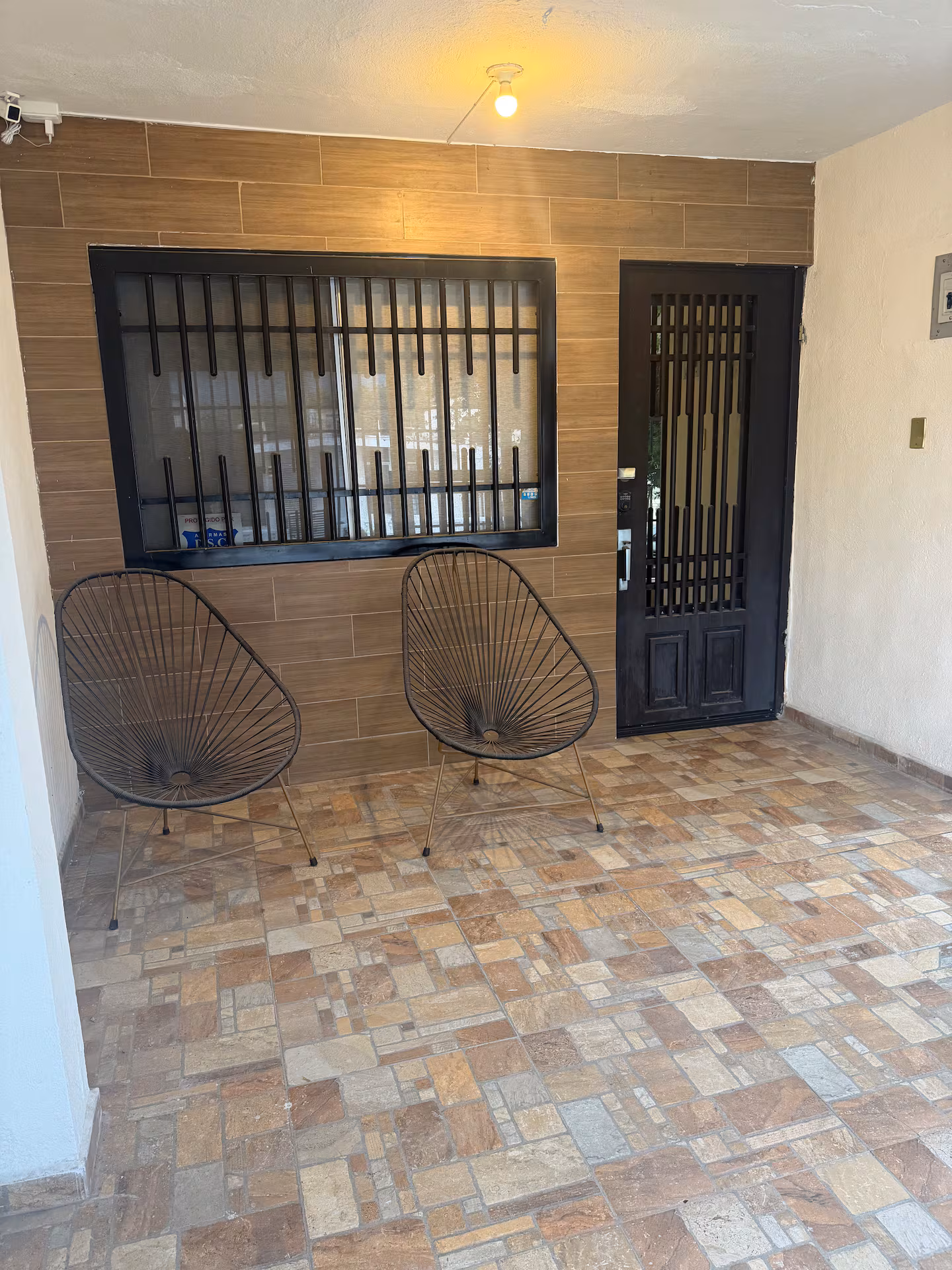Patio techado con sillas y entrada a la casa